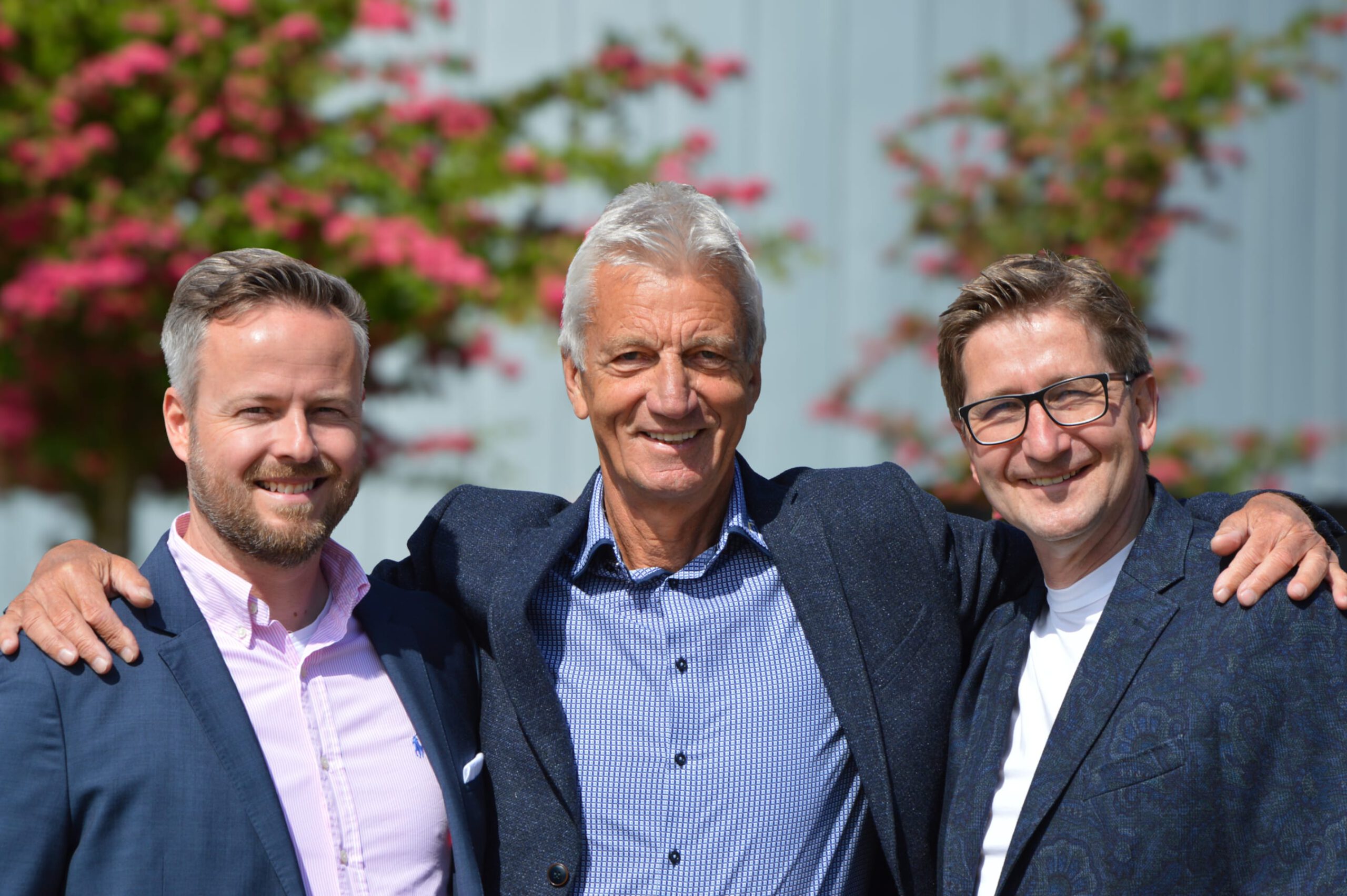 Drei Männer schauen lächelnd in die Kamera